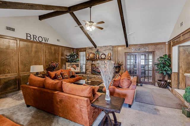 carpeted living room featuring ceiling fan, beam ceiling, high vaulted ceiling, a brick fireplace, and wood walls