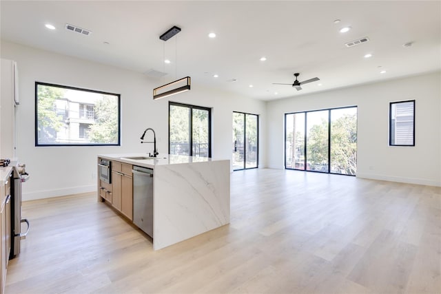 kitchen featuring sink, light hardwood / wood-style flooring, stainless steel appliances, light stone counters, and decorative light fixtures