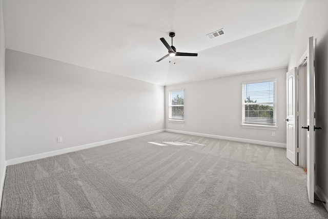 carpeted empty room with ceiling fan, vaulted ceiling, and a healthy amount of sunlight