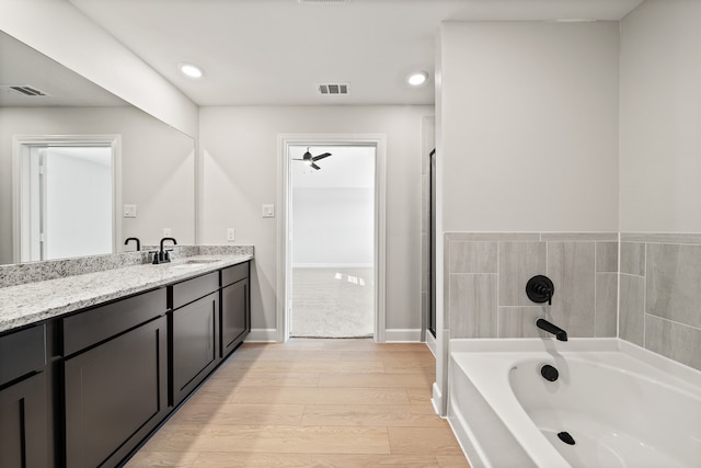 bathroom with hardwood / wood-style flooring, a bathing tub, and vanity