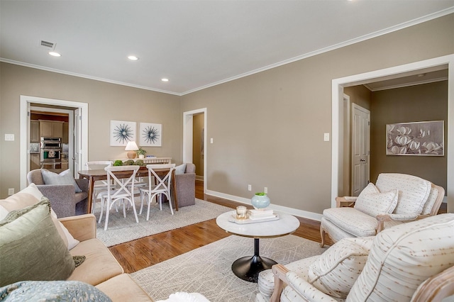 living area with recessed lighting, visible vents, ornamental molding, wood finished floors, and baseboards