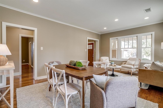 dining room with visible vents, crown molding, baseboards, and wood finished floors