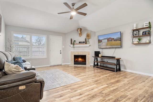 living area featuring vaulted ceiling, a fireplace, baseboards, and wood finished floors