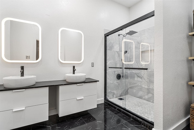 full bath featuring marble finish floor, a stall shower, and a sink