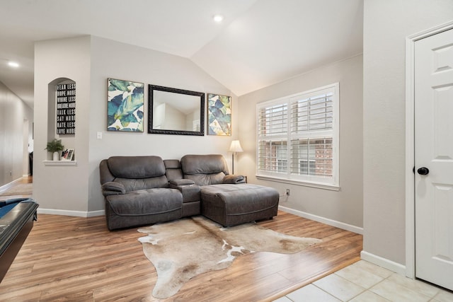 living room with vaulted ceiling, light wood-type flooring, and baseboards