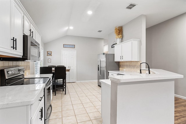 kitchen with tasteful backsplash, kitchen peninsula, white cabinets, and appliances with stainless steel finishes