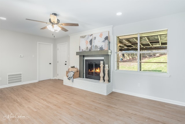 unfurnished living room with ceiling fan, light wood-type flooring, and a fireplace