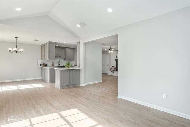 kitchen featuring gray cabinetry, decorative light fixtures, light hardwood / wood-style flooring, ceiling fan with notable chandelier, and decorative backsplash