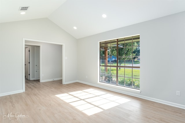 empty room with plenty of natural light, lofted ceiling, and light hardwood / wood-style floors