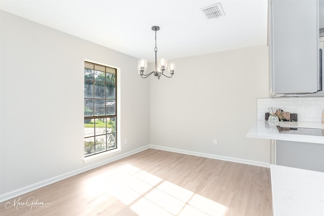 unfurnished dining area featuring a chandelier and light hardwood / wood-style floors