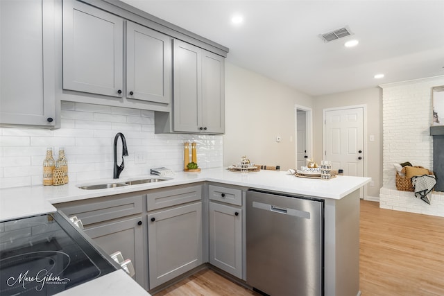 kitchen with dishwasher, sink, kitchen peninsula, and gray cabinetry