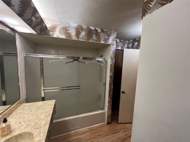 bathroom with enclosed tub / shower combo, vanity, hardwood / wood-style floors, and a textured ceiling