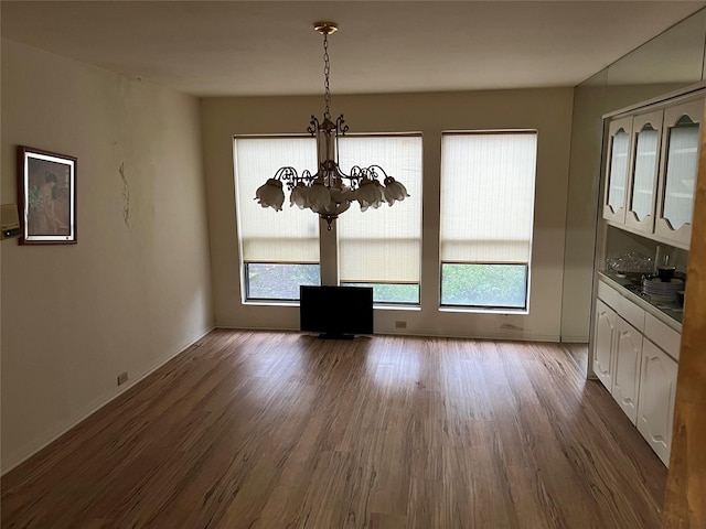 unfurnished dining area with hardwood / wood-style floors, a notable chandelier, and a wealth of natural light