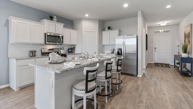 kitchen featuring white cabinetry, stainless steel appliances, and an island with sink