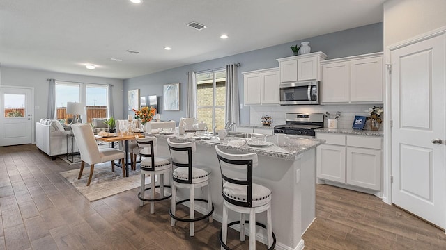 kitchen featuring stainless steel appliances, dark hardwood / wood-style floors, a kitchen island with sink, and white cabinets