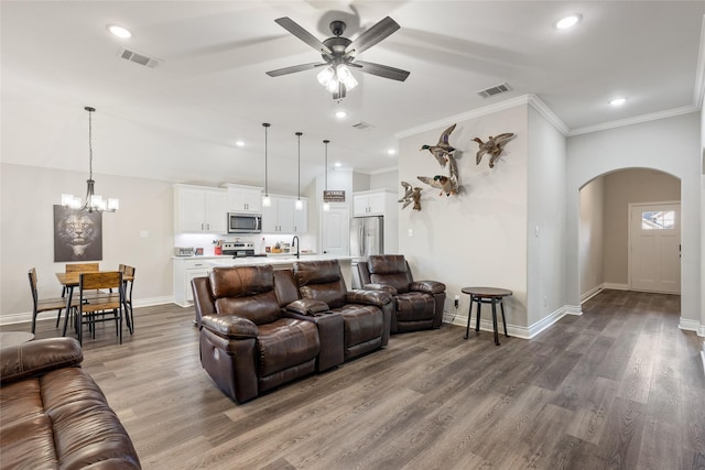 living room featuring ornamental molding, ceiling fan with notable chandelier, and dark hardwood / wood-style flooring