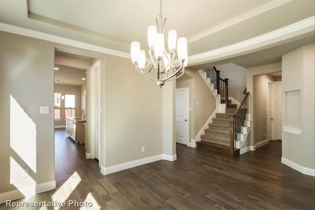 unfurnished dining area featuring an inviting chandelier, sink, a tray ceiling, and dark wood-type flooring