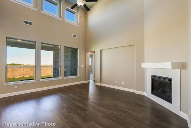 unfurnished living room with a tile fireplace, dark hardwood / wood-style floors, and ceiling fan