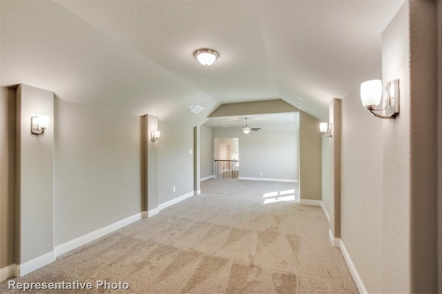 hallway featuring light colored carpet and vaulted ceiling