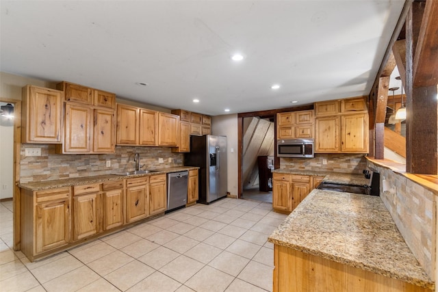 kitchen with light stone countertops, appliances with stainless steel finishes, sink, and light tile patterned floors