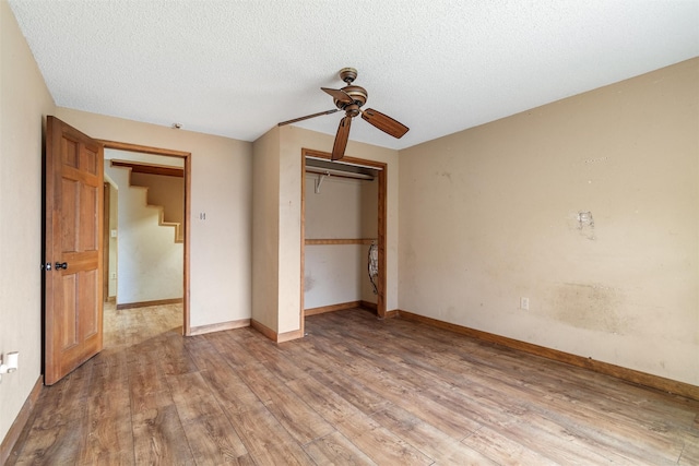 unfurnished bedroom featuring ceiling fan, a textured ceiling, light wood-type flooring, and a closet