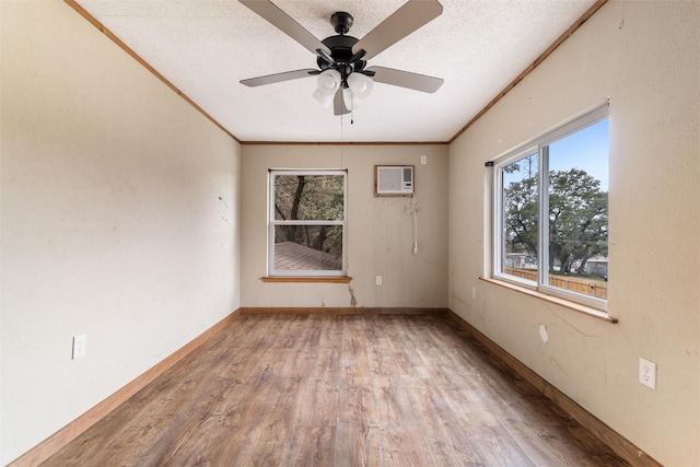 spare room featuring a wall mounted air conditioner, a textured ceiling, ornamental molding, ceiling fan, and light hardwood / wood-style floors