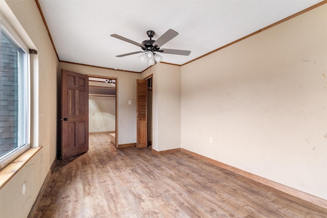 unfurnished bedroom with ceiling fan, ornamental molding, a closet, and light wood-type flooring