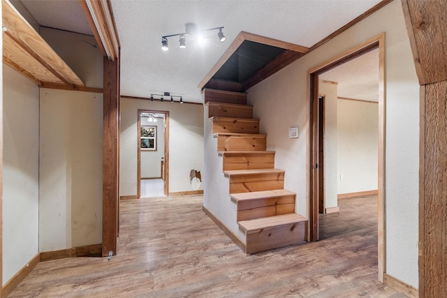 stairs with hardwood / wood-style flooring, track lighting, crown molding, and a textured ceiling