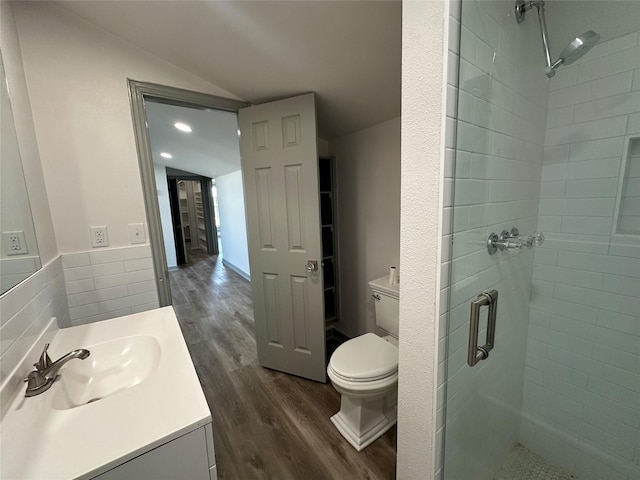 bathroom with vaulted ceiling, hardwood / wood-style floors, vanity, an enclosed shower, and toilet