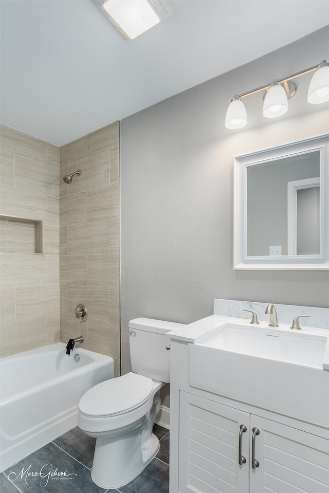 full bathroom with tile patterned flooring, vanity, tiled shower / bath, and toilet