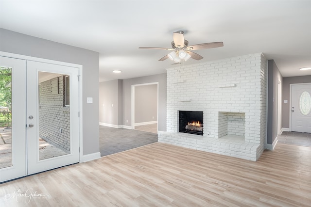 unfurnished living room featuring a fireplace, french doors, ceiling fan, and light wood-type flooring