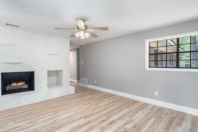 unfurnished living room with ceiling fan, a fireplace, and light hardwood / wood-style flooring