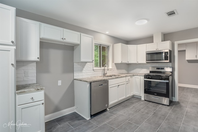 kitchen featuring light stone counters, stainless steel appliances, sink, and white cabinets