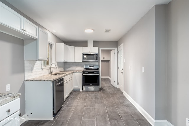 kitchen featuring tasteful backsplash, sink, white cabinets, stainless steel appliances, and light stone countertops