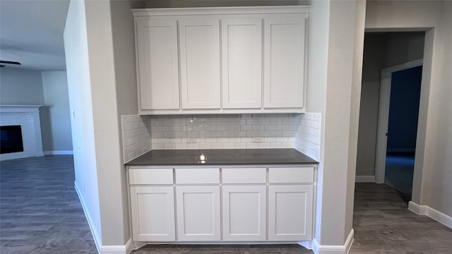kitchen with dark hardwood / wood-style flooring, a brick fireplace, decorative backsplash, and white cabinets