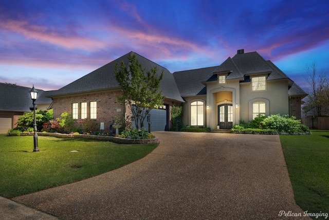 french provincial home featuring a garage and a lawn