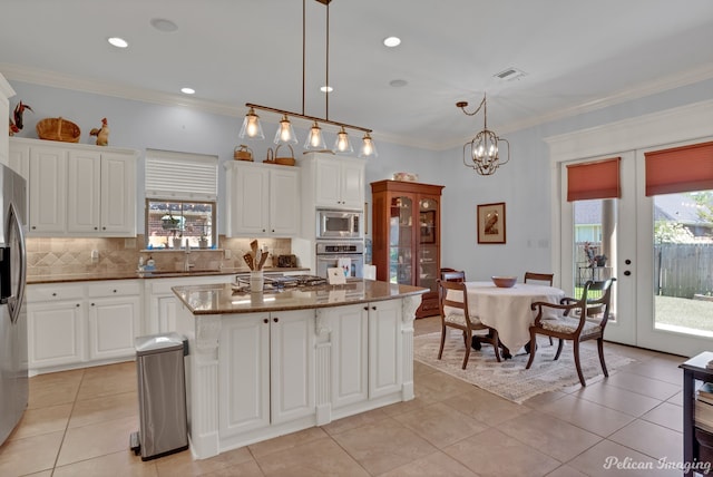 kitchen featuring stainless steel appliances, white cabinetry, a kitchen island, and decorative light fixtures