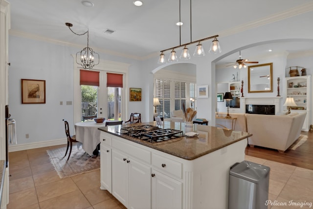 kitchen featuring crown molding, dark stone counters, a kitchen island, and white cabinets