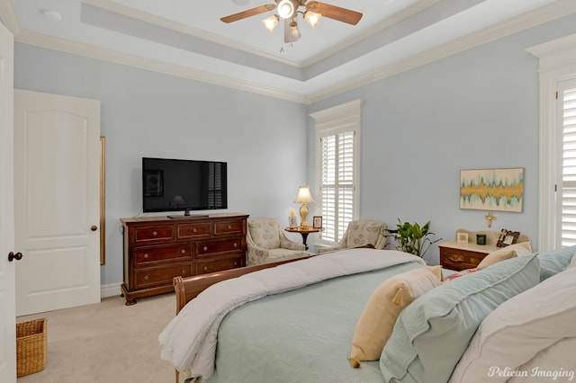 carpeted bedroom featuring a tray ceiling, ornamental molding, and ceiling fan