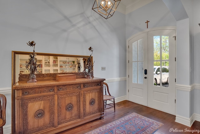 foyer entrance featuring dark wood-type flooring, french doors, and a chandelier