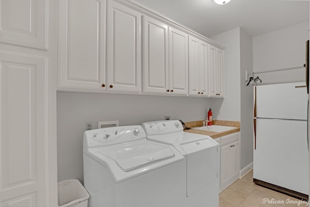 washroom with sink, washing machine and dryer, and cabinets