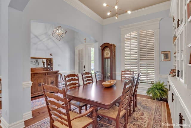 dining room with an inviting chandelier, ornamental molding, light hardwood / wood-style flooring, and french doors