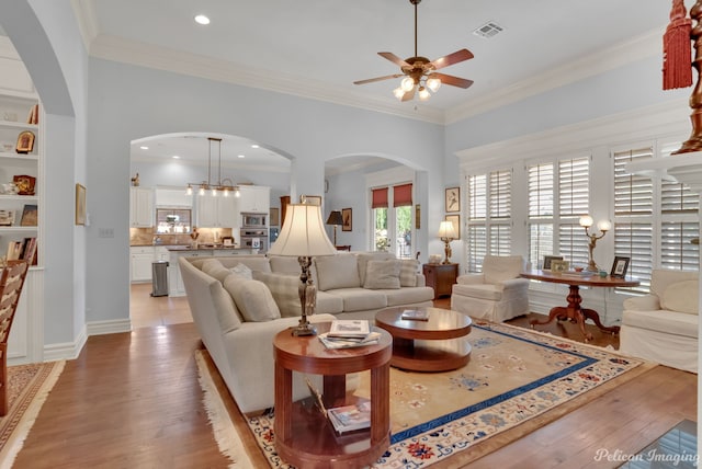 living room featuring ornamental molding, light hardwood / wood-style floors, and ceiling fan