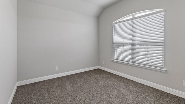 carpeted empty room featuring vaulted ceiling