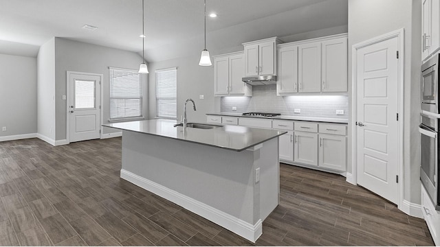 kitchen with sink, appliances with stainless steel finishes, an island with sink, white cabinets, and decorative light fixtures