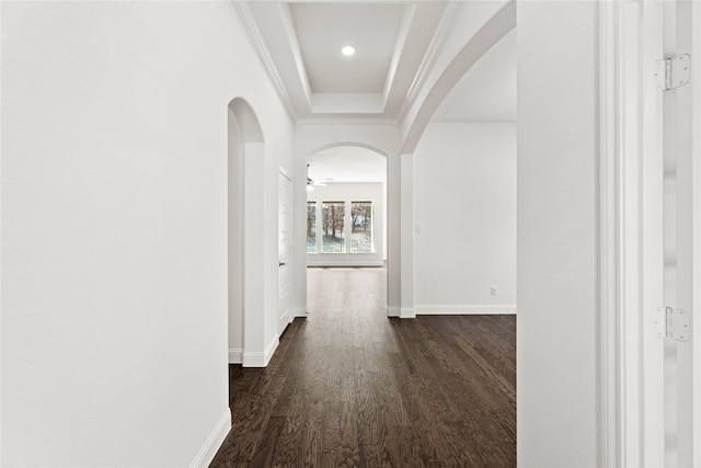 hall with crown molding, dark wood-type flooring, and a tray ceiling