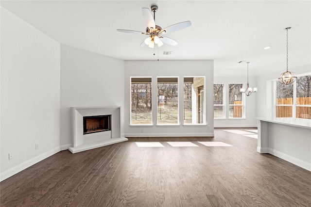 unfurnished living room with dark hardwood / wood-style flooring and ceiling fan with notable chandelier