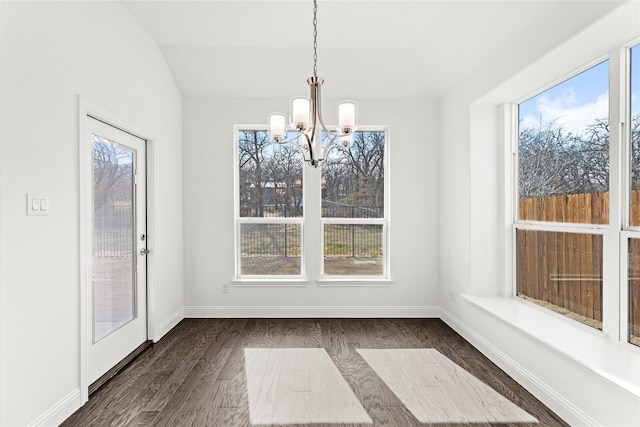 unfurnished dining area with a healthy amount of sunlight, dark hardwood / wood-style flooring, a chandelier, and vaulted ceiling