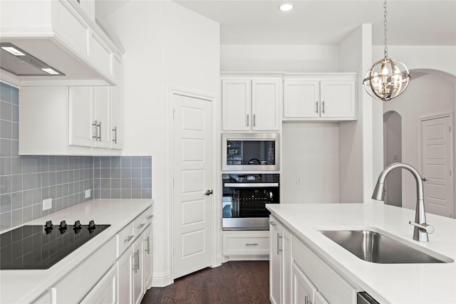 kitchen with pendant lighting, tasteful backsplash, white cabinetry, sink, and stainless steel appliances