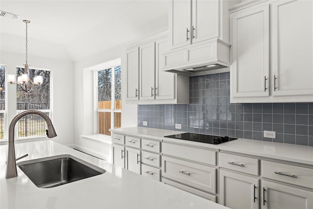 kitchen featuring tasteful backsplash, sink, white cabinets, hanging light fixtures, and black electric cooktop